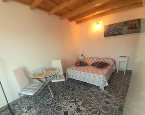 A small, cozy room with a bed, a table with chairs, and a patterned floor. - Estudio Dominicana in Albufeira Gale (Albufeira)