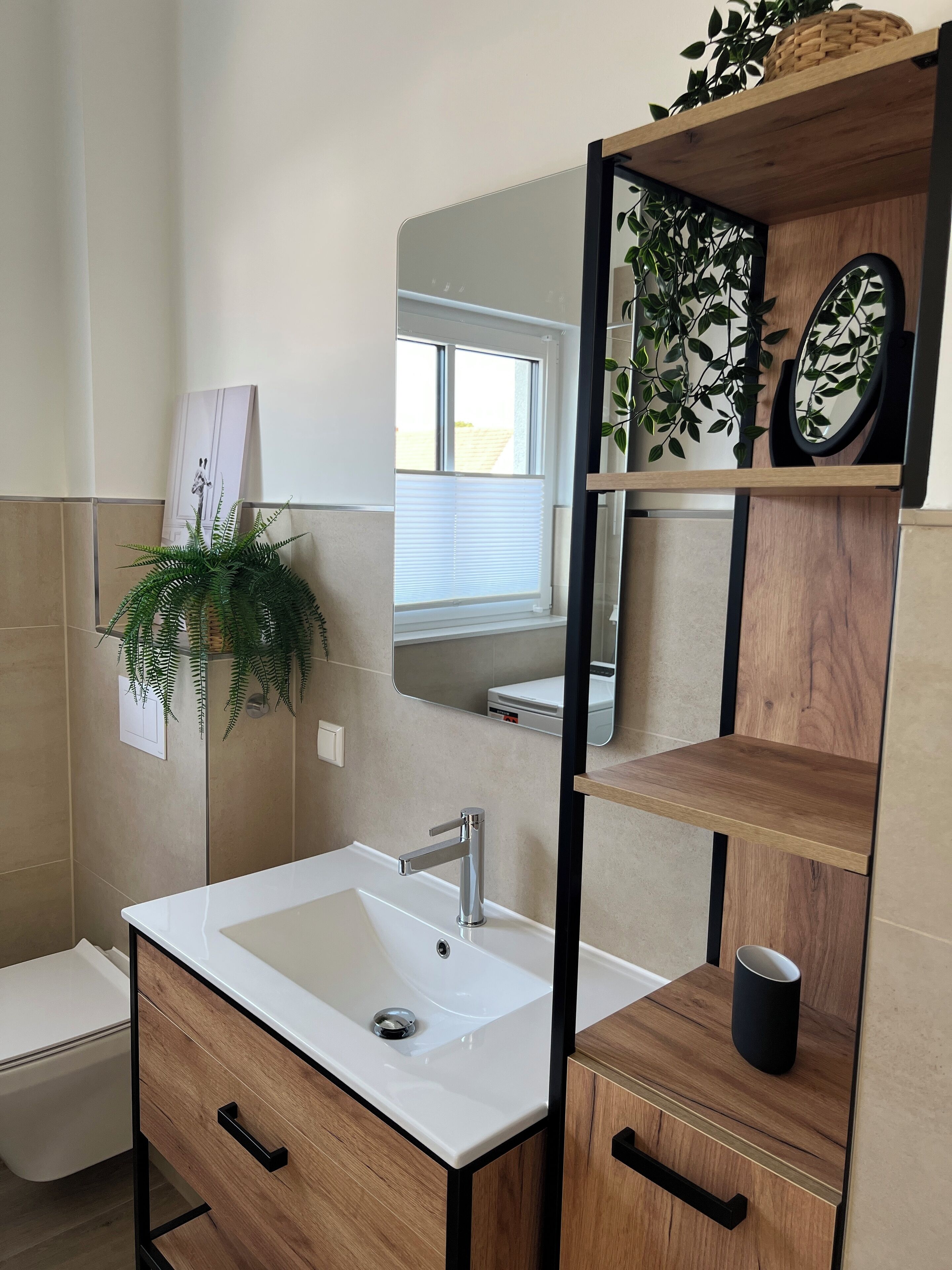 Ein modernes Badezimmer mit einem weißen Waschbecken, Holzschränken und einem Spiegel darüber.