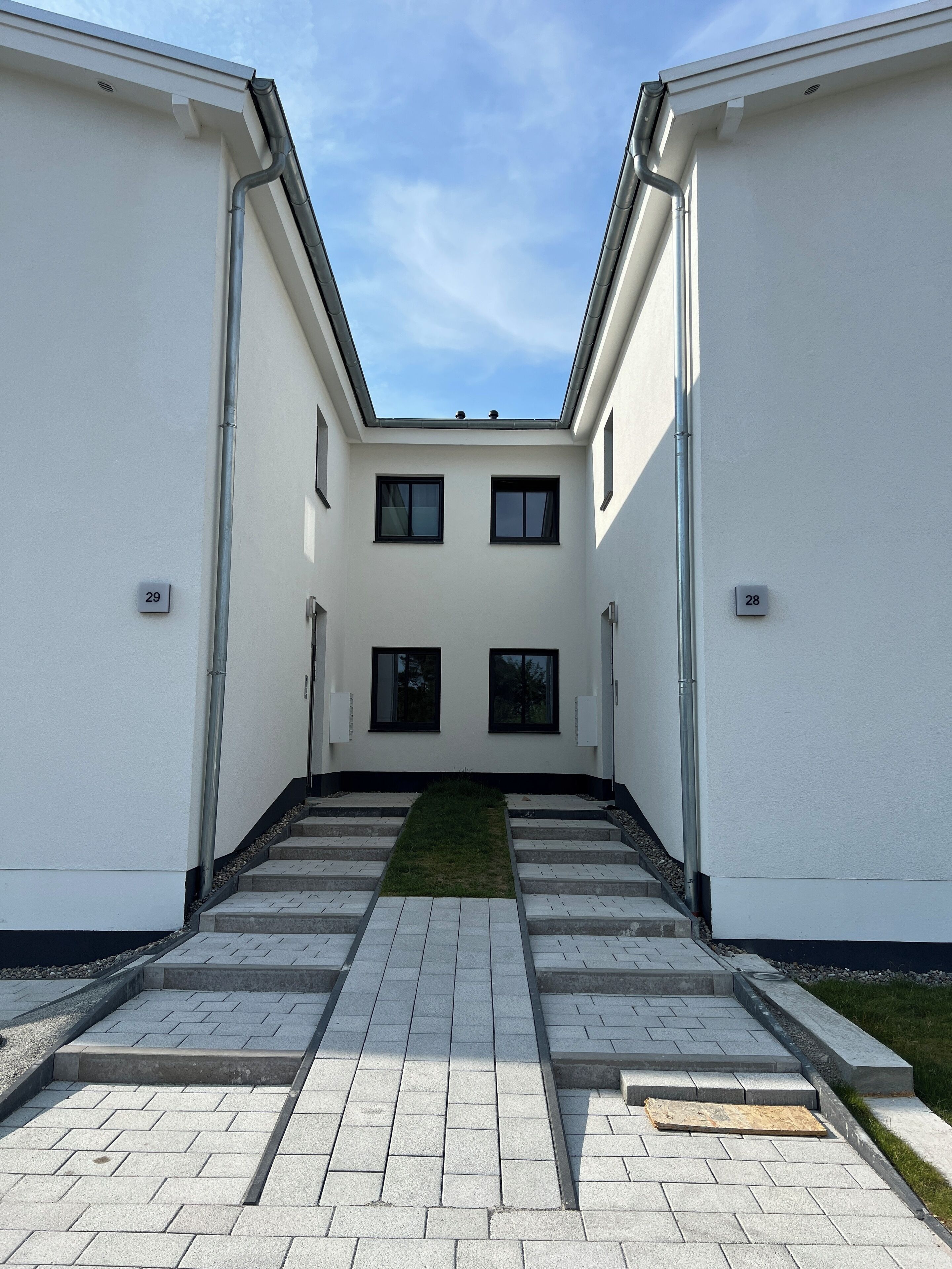 Een modern gebouw met een centrale binnenplaats, twee kleine ramen en een plat dak.