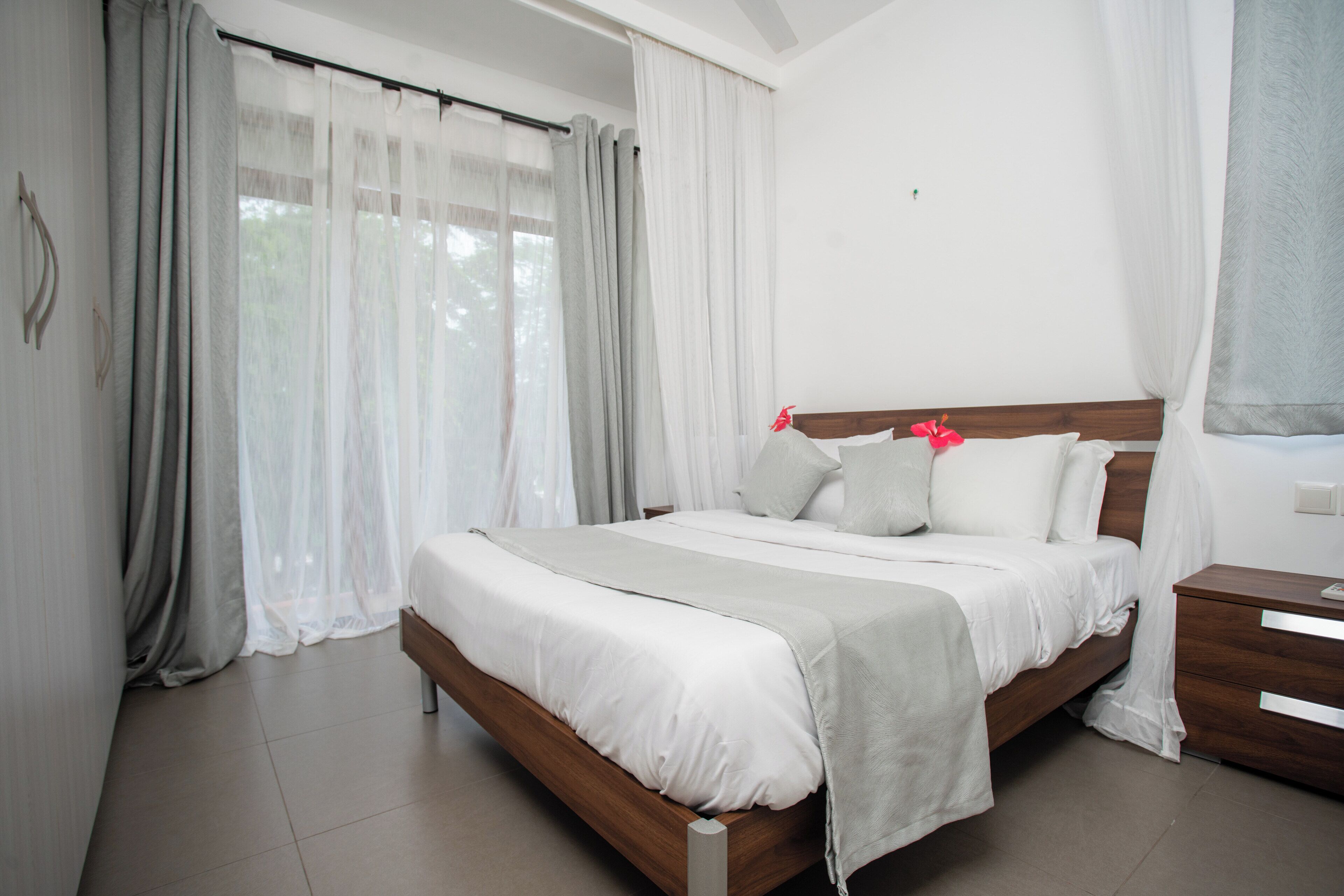 Un dormitorio con una cama de madera, ropa de cama blanca y una mesita de noche.
