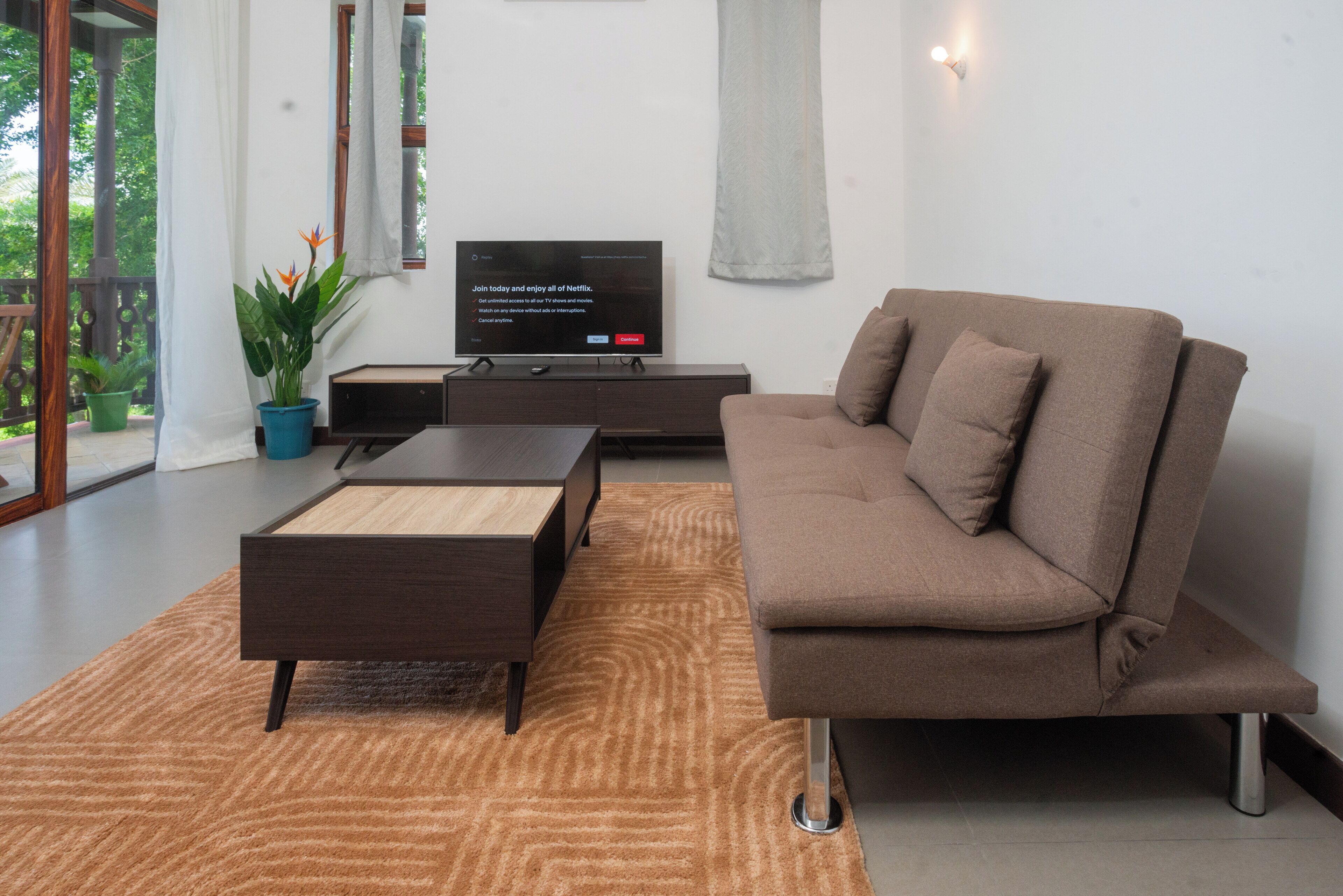 A modern living room with a brown sofa, a coffee table, and a flat-screen TV on a stand.