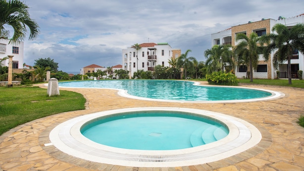 A resort with a large swimming pool, a smaller circular pool, and a well-maintained lawn area.