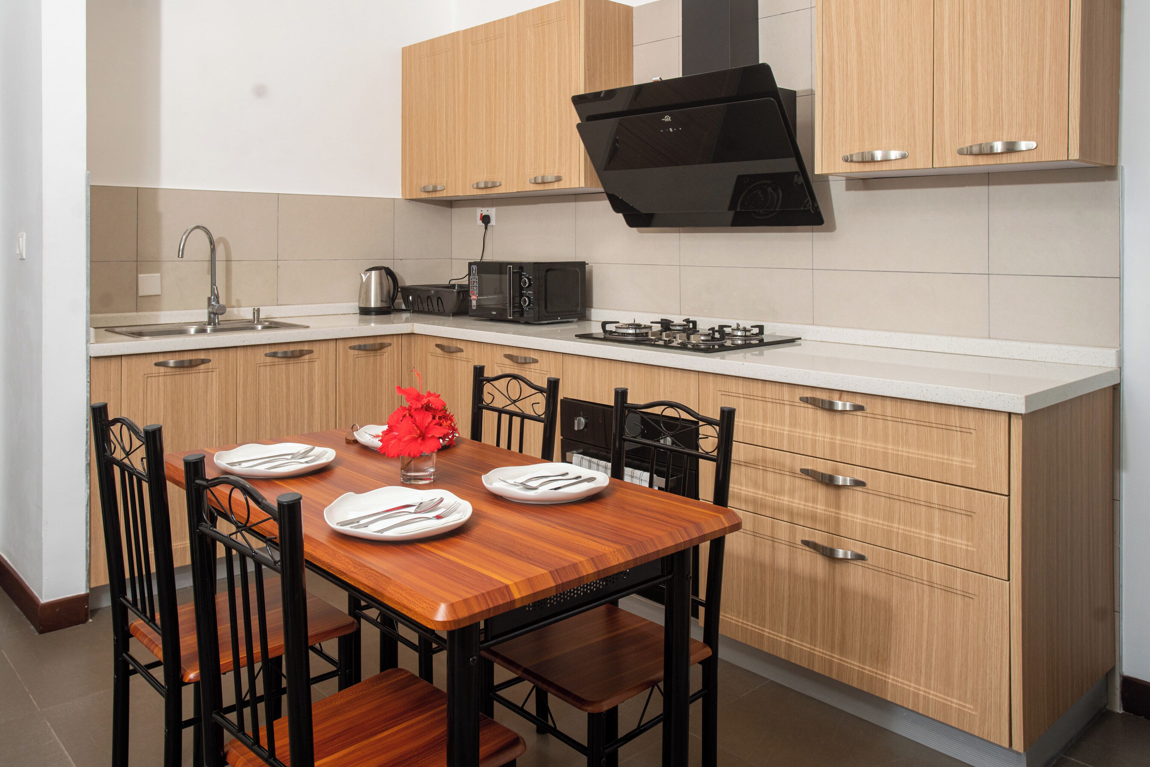 A modern kitchen with wooden cabinets, a built-in stove, and a dining table set for four.
