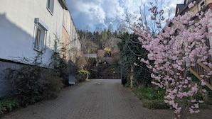 Un sendero pavimentado que conduce a un edificio con fachada blanca y pared de ladrillo.