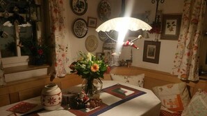 Una habitación acogedora con un banco de madera, una mesa con colcha y un jarrón con flores.