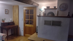 Una habitación acogedora con una puerta de madera, una pequeña mesa, un reloj y un estante con objetos decorativos.