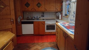 Una cocina compacta con armarios de madera, horno empotrado, lavavajillas y una alfombra roja.