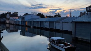 A calm river with a boat docked near buildings with flat roofs. - Enjoy a Boathouse on the Bay in the heart of Downtown Sandusky.  (Sandusky)