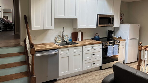 A modern kitchen with white cabinets, a stainless steel dishwasher, a microwave, and a refrigerator. - Enjoy a Boathouse on the Bay in the heart of Downtown Sandusky.  (Sandusky)