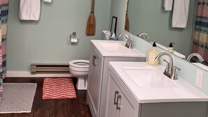 A bathroom with two sinks, a mirror, a wooden paddle, and a toilet. - Enjoy a Boathouse on the Bay in the heart of Downtown Sandusky.  (Sandusky)