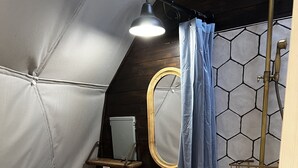 A compact bathroom with a toilet, sink, and shower area. -  Red Owl Retreat: The Peaks Geodesic Dome  (Bigfork)