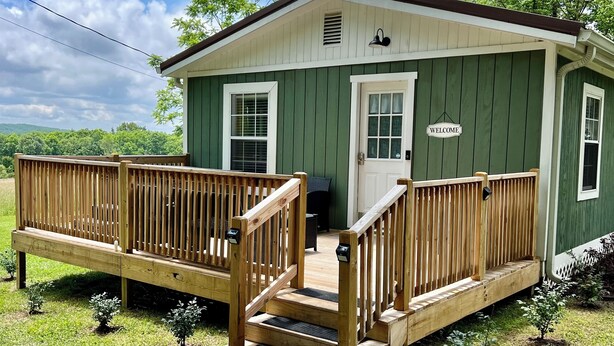 A small, single-story house with a green exterior and a wooden porch. - August special ✨99.00✨night!2B-2B cottage-hot tub-by Fall Creek Falls Park. (Spencer)