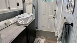 A laundry room with a washing machine, a drying rack, and a door with a window. - August special ✨99.00✨night!2B-2B cottage-hot tub-by Fall Creek Falls Park. (Spencer)