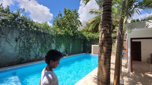 A swimming pool with a tiled edge, surrounded by a wall covered in greenery and palm trees. - Green Oasis Hotel (La Romana)