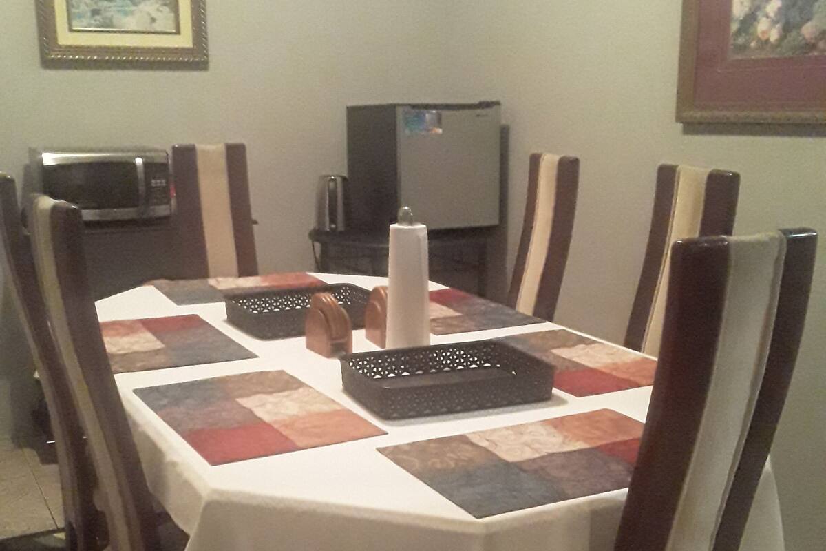 Una mesa de comedor con mantel blanco, rodeada de sillas de madera con diseños blanco y negro.