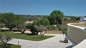 Una terraza en la azotea con un balcón curvo, un área pavimentada y vistas del paisaje y edificios circundantes.