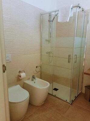A modern bathroom with a glass-enclosed shower, a bidet, and a toilet. - Agriturismo Cutura Agri Resort (Parabita)