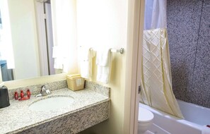 A bathroom with a granite sink, white towels, a toilet, and a shower curtain. - Days Inn By Wyndham College Park Atlanta Airport South (College Park)
