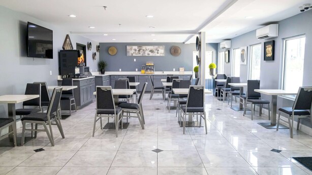 Un comedor moderno con cocina a la vista, que incluye un televisor de pantalla plana, una cafetera y diversas opciones de asiento.