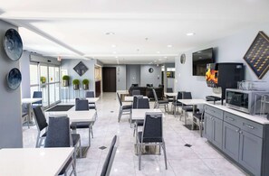 A modern dining area with tables and chairs, a microwave, and a television on the wall. - Days Inn By Wyndham College Park Atlanta Airport South (College Park)
