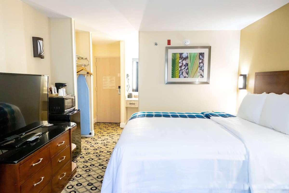 Ein Hotelzimmer mit Bett, Fernseher, Schminktisch, Mikrowelle und einem Bild an der Wand.