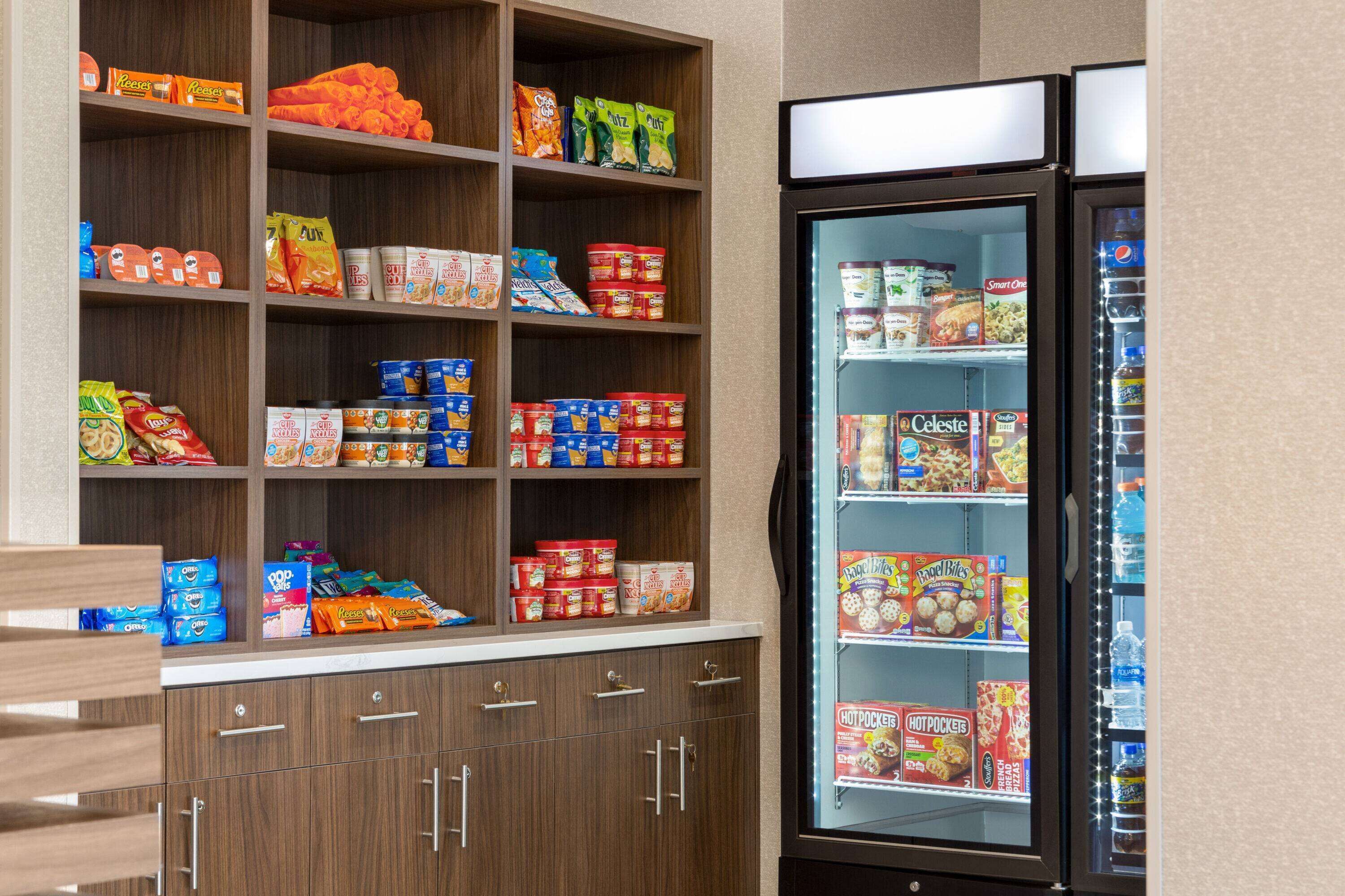 A self-service snack and beverage area with shelves stocked with various snacks and a refrigerated display case.