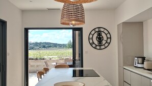 A modern kitchen with a marble island, a woven pendant light, and a view of a vineyard through the open door. - Air-conditioned villa, heated pool, vineyard view, calm setting (Pont-Saint-Esprit)