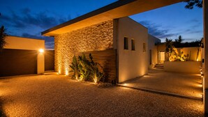 Un bâtiment moderne avec une façade en pierre, un garage et une allée gravillonnée.