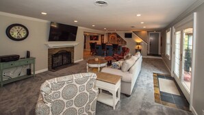 A spacious living room with a fireplace, a television, and a dining area in the background. - Large Home - Bar - Hot Tub - Private Back Yard (Louisville)