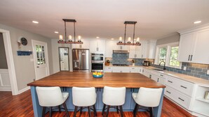 A spacious kitchen with a large island, white cabinetry, and a blue backsplash. - Large Home - Bar - Hot Tub - Private Back Yard (Louisville)