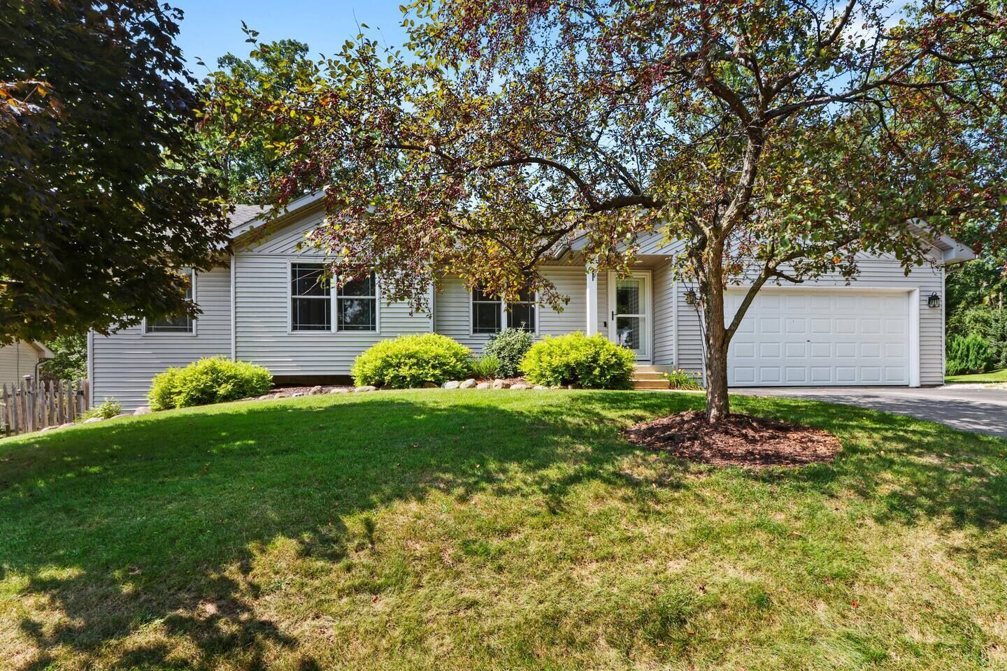 A single-story house with a front yard, a garage, and a tree.