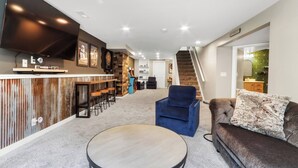 Uma sala de estar moderna com área de bar, escada e sofá.