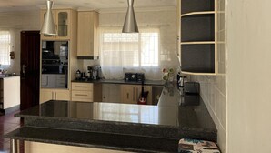 A modern kitchen with granite countertops, stainless steel appliances, and pendant lighting. - Remarkable 5-bed House in Springs & Nigel (Nigel)