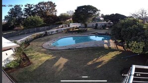 A backyard with a swimming pool, surrounded by a fence and various plants. - Remarkable 5-bed House in Springs & Nigel (Nigel)