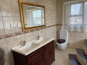 Une salle de bain avec deux lavabos, des toilettes et une baignoire.