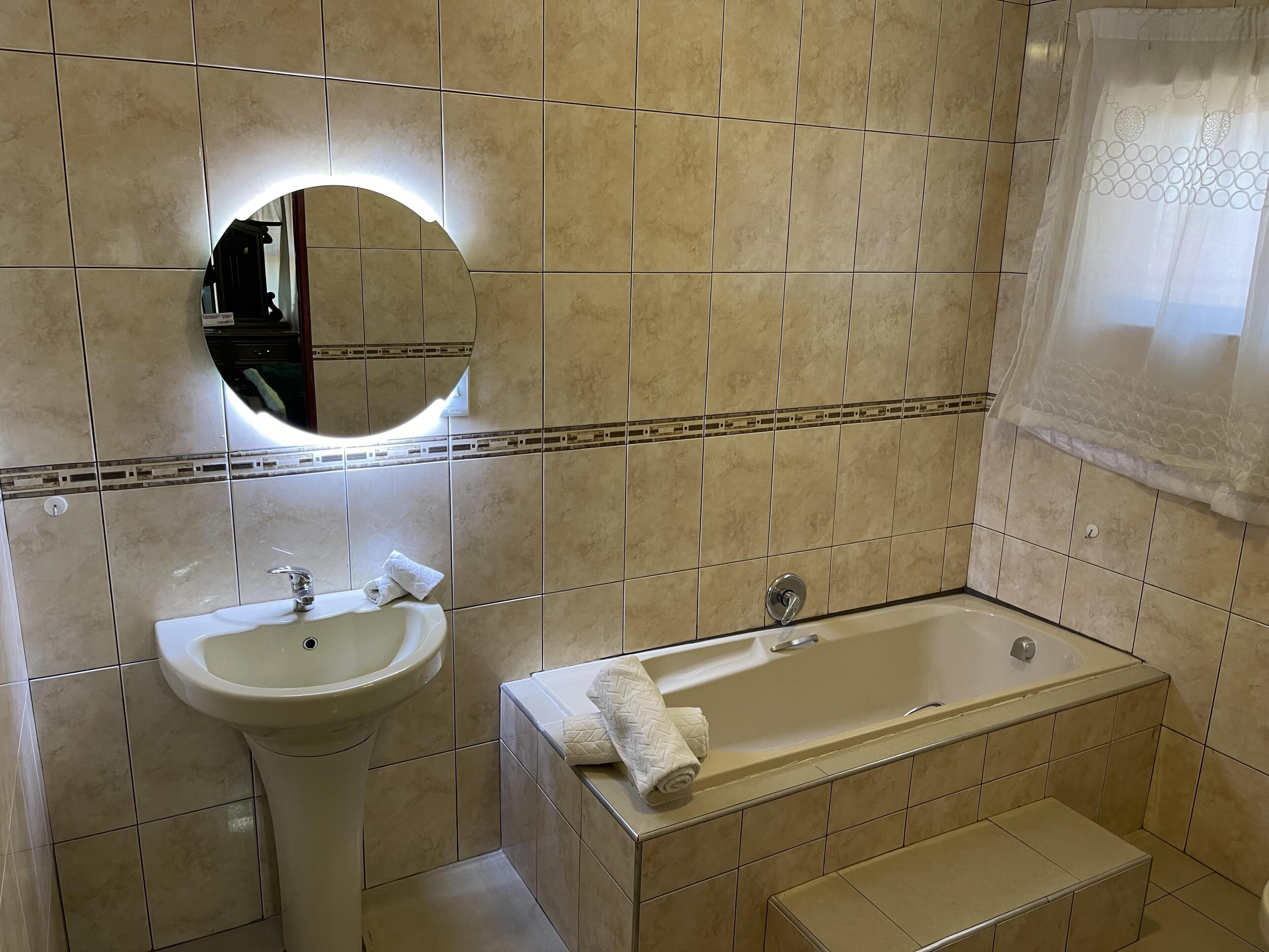 Un baño con lavamanos, espejo y bañera.