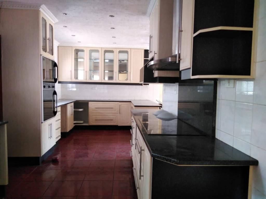 A kitchen with light-colored cabinets, a black countertop, and a tiled backsplash.