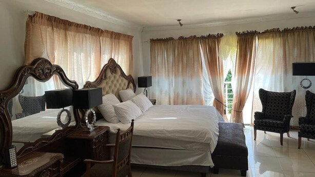 A hotel room with a large bed, two bedside tables, a chair, and a desk. - Remarkable 5-bed House in Springs & Nigel (Nigel)