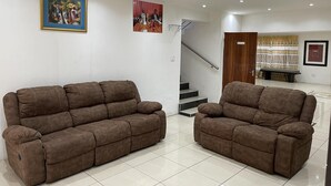 A spacious living area with two brown sofas, a staircase, and a bench. - Remarkable 5-bed House in Springs & Nigel (Nigel)