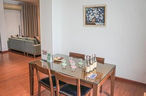 Un'area pranzo con un tavolo in vetro, sedie di legno e un quadro floreale incorniciato appeso al muro.