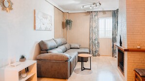 A modern living room with a sectional sofa, a small round table, and a fireplace.