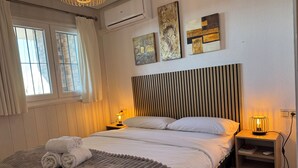 A neatly arranged bedroom with a large bed, a bedside table with a lamp, and artwork on the wall.