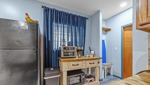 A compact kitchen with a refrigerator, microwave, and a wooden cabinet with drawers. - Roos&Blues lake house. City park steps away. Rm for 6, king beds, pets friendly (Madisonville)