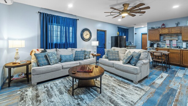 A living room with two sofas, a coffee table, and a kitchen area with wooden cabinets and a dining table. - Roos&Blues lake house. City park steps away. Rm for 6, king beds, pets friendly (Madisonville)