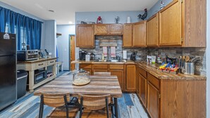 A kitchen with wooden cabinets, a granite countertop, a built-in oven, and a dining area with a wooden table and chairs. - Roos&Blues lake house. City park steps away. Rm for 6, king beds, pets friendly (Madisonville)