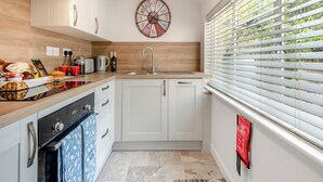 Een moderne keuken met witte kastjes, een houten aanrecht, een spoelbak en een klok aan de muur.