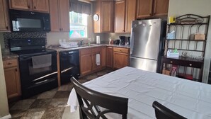 A kitchen with wooden cabinets, a stainless steel refrigerator, a microwave, and a stove.