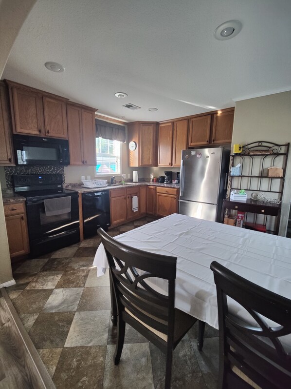 A kitchen with wooden cabinets, a stainless steel refrigerator, a microwave, and a stove.