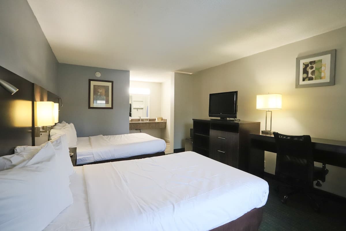 Una habitación de hotel con dos camas, un escritorio, un televisor y una lámpara.