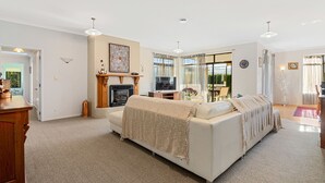 Een ruime woonkamer met een open haard, een bank, een televisie en een eethoek met een tafel en stoelen.